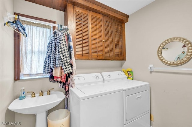 clothes washing area featuring washer and dryer, cabinets, and sink