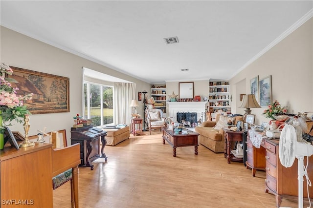 sitting room featuring built in features, ornamental molding, and light hardwood / wood-style flooring