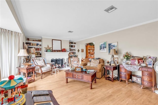 living room with light hardwood / wood-style floors, built in shelves, and ornamental molding