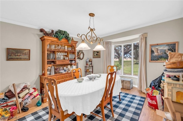 dining room with crown molding and light hardwood / wood-style flooring