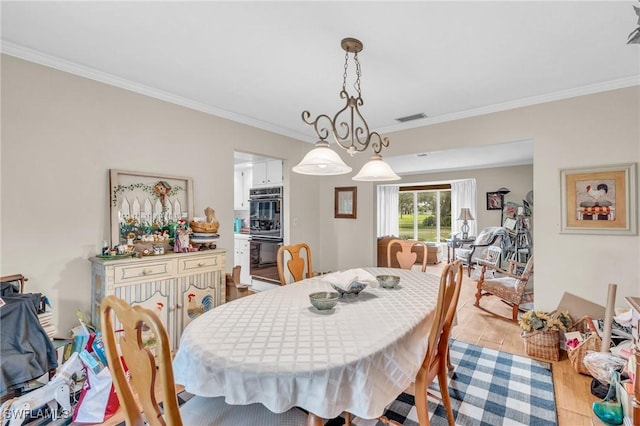 dining space with crown molding and light hardwood / wood-style flooring