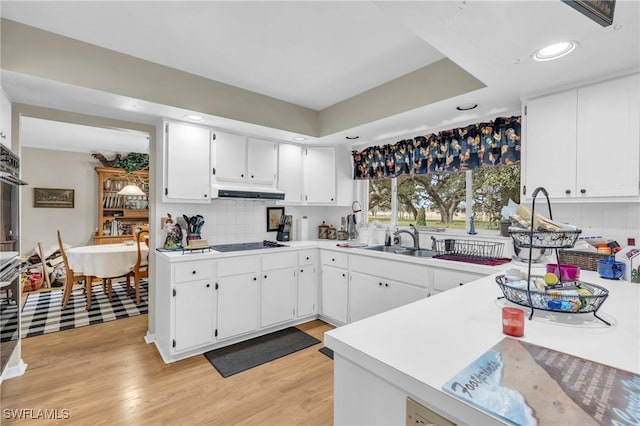 kitchen with white cabinetry, light hardwood / wood-style floors, black electric cooktop, and tasteful backsplash