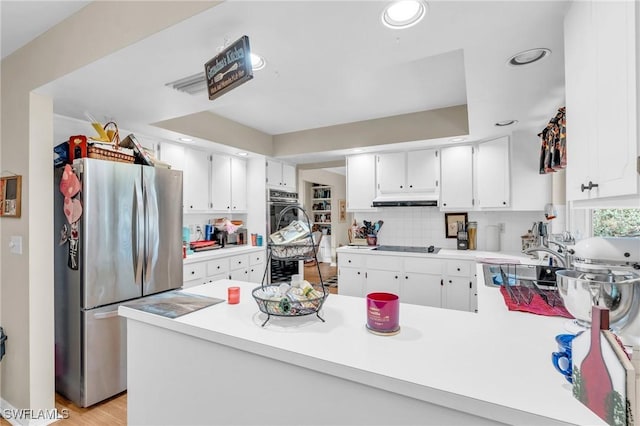 kitchen with white cabinetry, kitchen peninsula, appliances with stainless steel finishes, backsplash, and sink