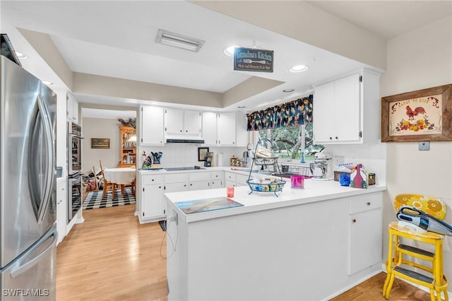 kitchen featuring stainless steel fridge, black electric stovetop, backsplash, white cabinets, and light hardwood / wood-style flooring