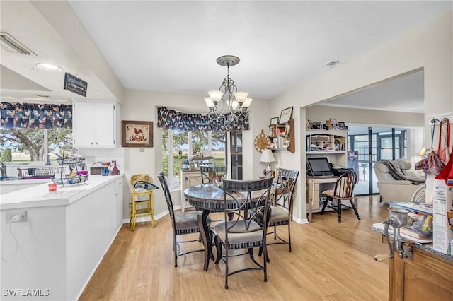 dining room featuring a notable chandelier, plenty of natural light, and light hardwood / wood-style floors