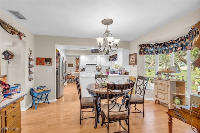 dining space featuring light wood-type flooring and a notable chandelier