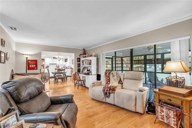 living room featuring light wood-type flooring, ceiling fan with notable chandelier, and ornamental molding