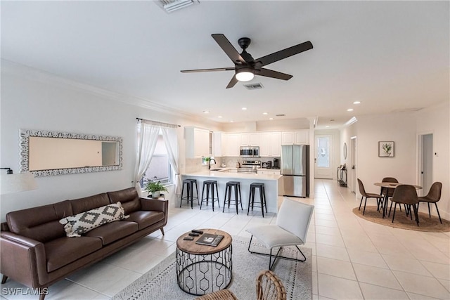 tiled living room featuring ceiling fan, sink, and ornamental molding