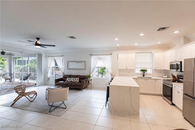 kitchen with a breakfast bar area, stainless steel appliances, ornamental molding, white cabinets, and a center island