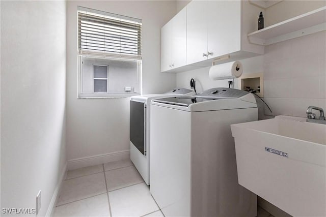 laundry room with cabinets, sink, washing machine and dryer, and light tile patterned flooring