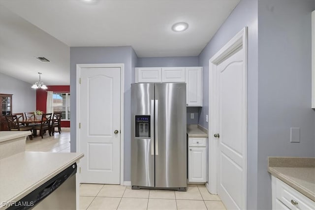 kitchen with appliances with stainless steel finishes, pendant lighting, white cabinetry, light tile patterned floors, and a notable chandelier