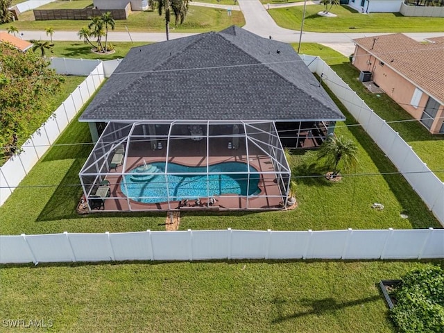 view of pool with a patio area, glass enclosure, and a lawn