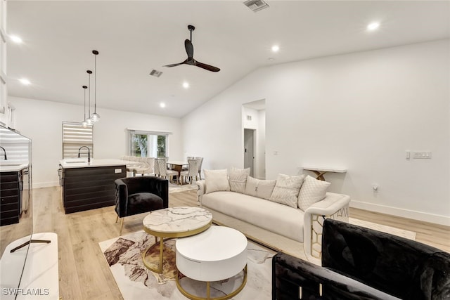 living room with ceiling fan, lofted ceiling, light hardwood / wood-style floors, and sink