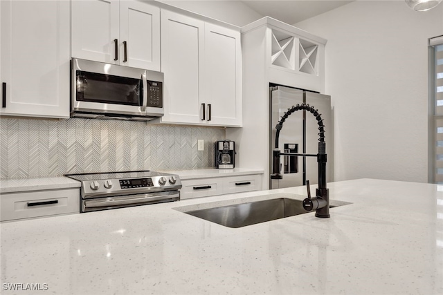 kitchen featuring appliances with stainless steel finishes, light stone countertops, and white cabinets