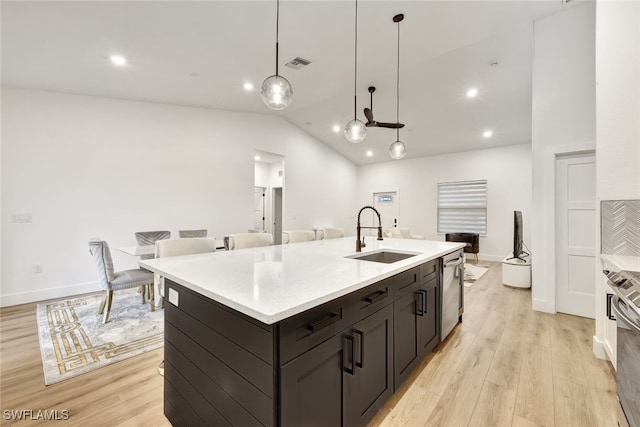 kitchen featuring pendant lighting, sink, a kitchen island with sink, stainless steel dishwasher, and light hardwood / wood-style floors