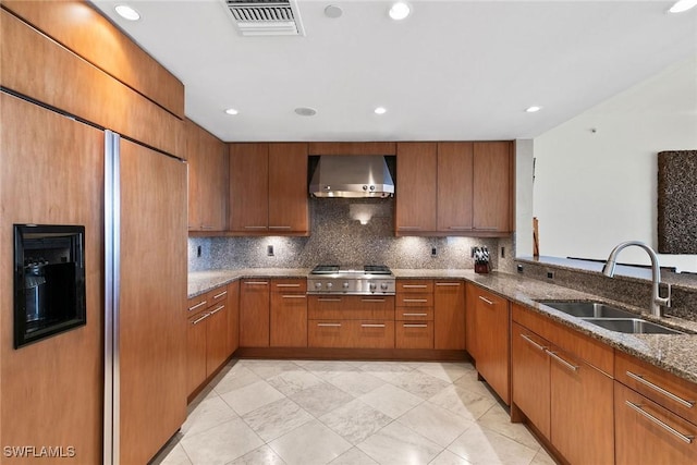 kitchen featuring sink, wall chimney exhaust hood, decorative backsplash, dark stone counters, and stainless steel gas stovetop