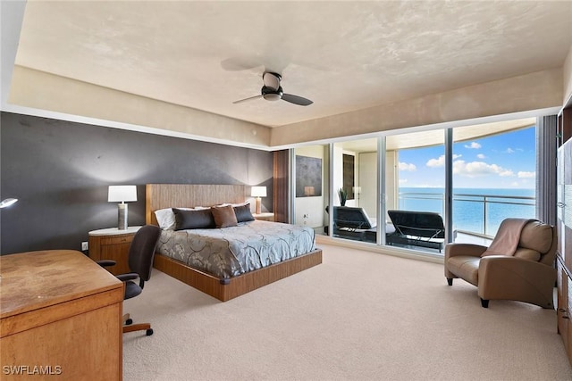 bedroom with a water view, ceiling fan, light carpet, and access to outside