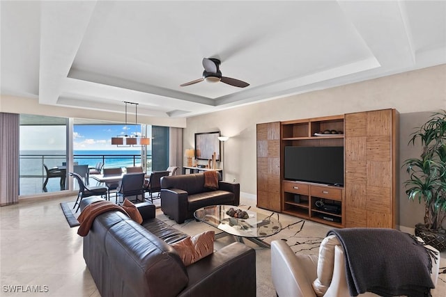 living room with a tray ceiling, ceiling fan, and a water view