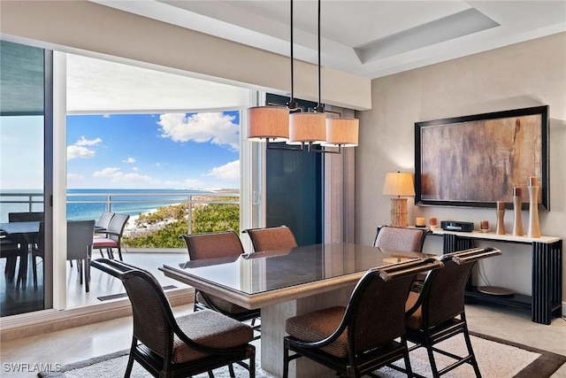 dining area featuring a water view and a tray ceiling