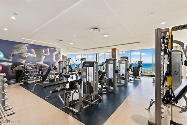 exercise room with floor to ceiling windows and a water view