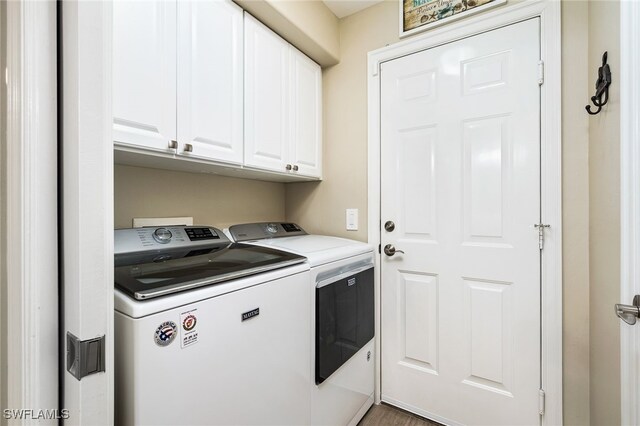 clothes washing area featuring washer and clothes dryer and cabinets