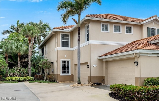 view of front of home featuring a garage, a tiled roof, concrete driveway, and stucco siding