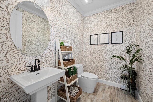 bathroom featuring sink, crown molding, wood-type flooring, and toilet