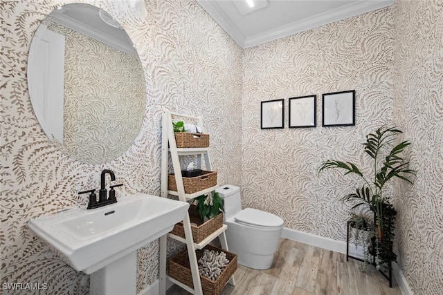 bathroom with ornamental molding, a sink, toilet, and wallpapered walls