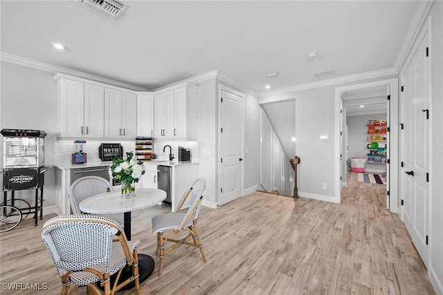 kitchen featuring dishwasher, white cabinetry, backsplash, ornamental molding, and light wood-type flooring