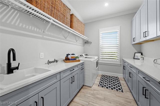 laundry area featuring sink, cabinets, independent washer and dryer, light hardwood / wood-style floors, and ornamental molding