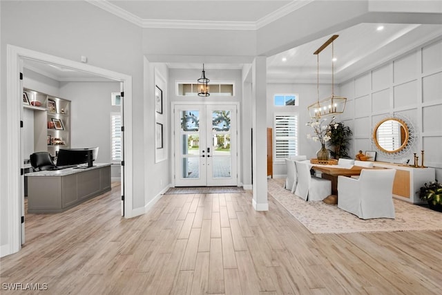 entrance foyer featuring french doors, light wood finished floors, ornamental molding, a chandelier, and baseboards