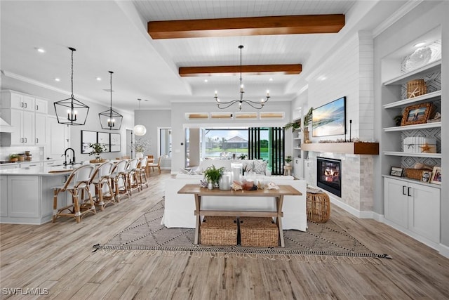 living room featuring beamed ceiling, built in shelves, an inviting chandelier, and light hardwood / wood-style floors