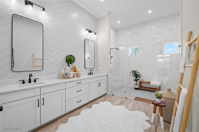 bathroom featuring hardwood / wood-style flooring, tiled shower, and vanity