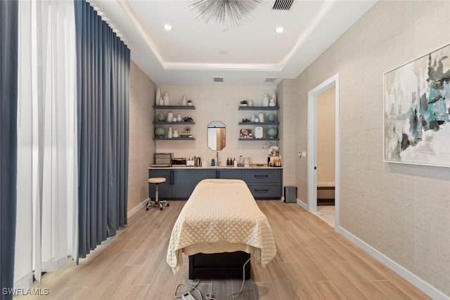 bedroom featuring a tray ceiling, wood finish floors, visible vents, and recessed lighting