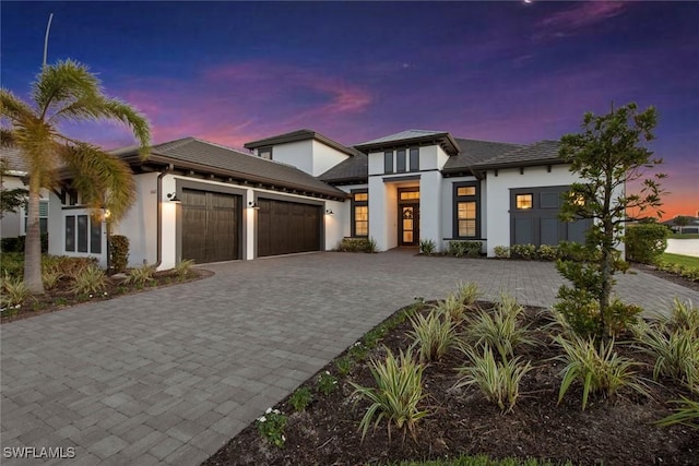 view of front of house featuring decorative driveway, an attached garage, and stucco siding