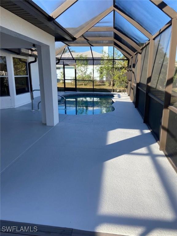 view of swimming pool with glass enclosure and a patio