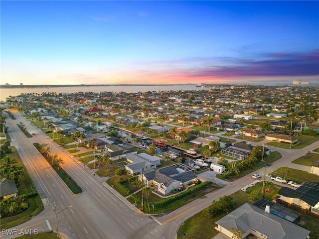 aerial view at dusk featuring a water view