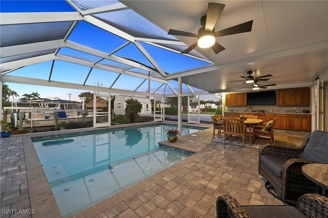 view of pool featuring ceiling fan, exterior bar, glass enclosure, and a patio area