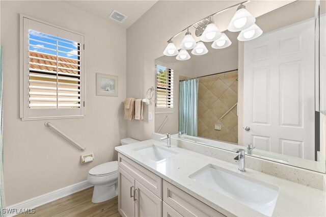 bathroom featuring wood-type flooring, toilet, vanity, and walk in shower