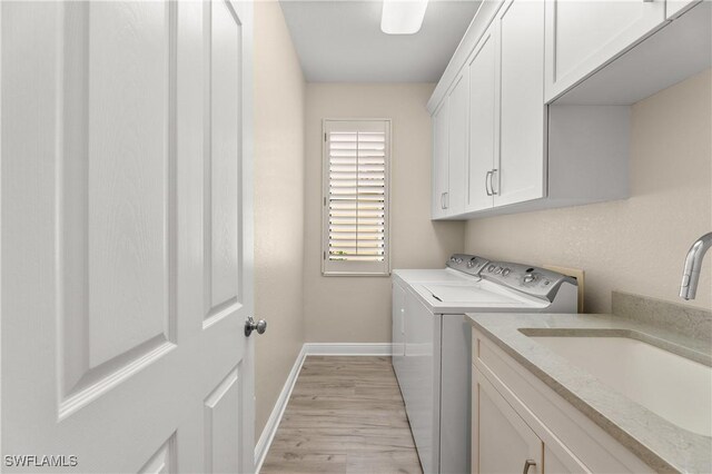 washroom featuring washing machine and dryer, light hardwood / wood-style flooring, cabinets, and sink