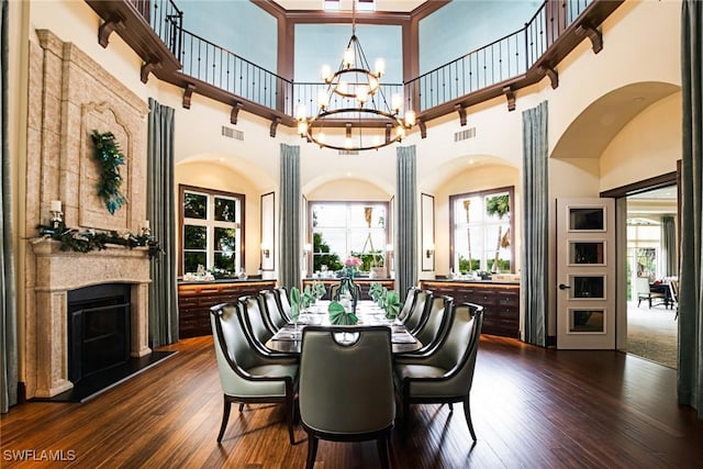 dining space featuring a towering ceiling, a notable chandelier, and dark hardwood / wood-style flooring