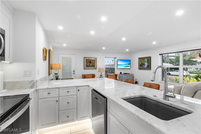 kitchen featuring light stone countertops, kitchen peninsula, dishwasher, and sink