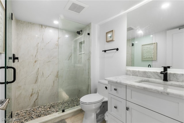 bathroom with a shower with shower door, toilet, vanity, and tile patterned flooring