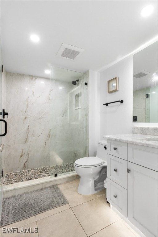 bathroom with a shower with door, toilet, vanity, and tile patterned flooring