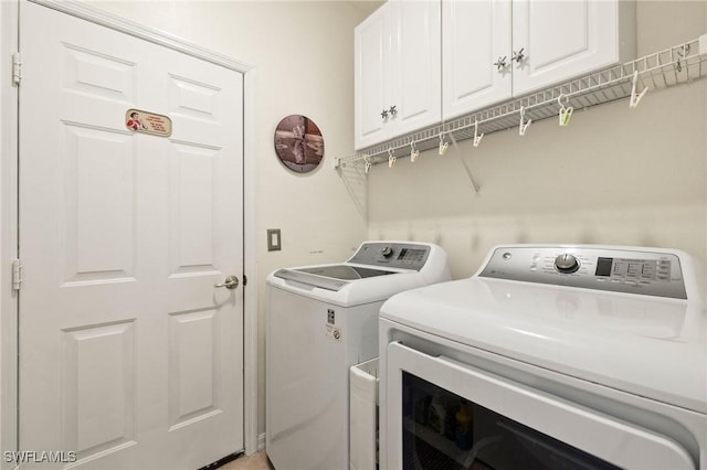 clothes washing area with cabinets and washer and dryer