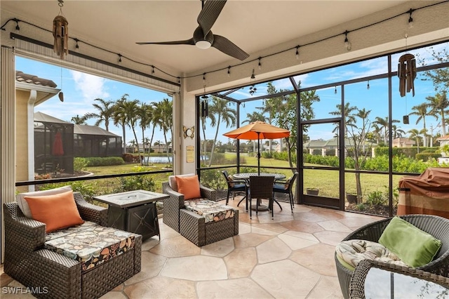 sunroom featuring ceiling fan and a water view