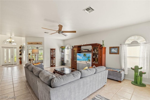 tiled living room with ceiling fan with notable chandelier