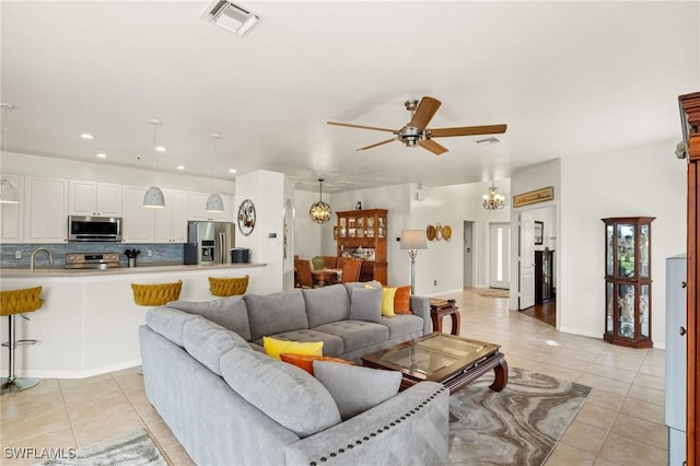 living room with ceiling fan with notable chandelier, sink, and light tile patterned floors