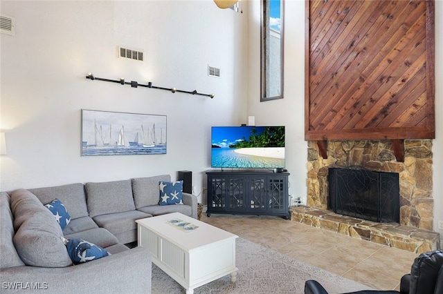 tiled living room featuring a high ceiling, visible vents, and a fireplace