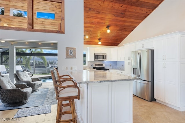 kitchen with light stone countertops, white cabinetry, wood ceiling, and appliances with stainless steel finishes